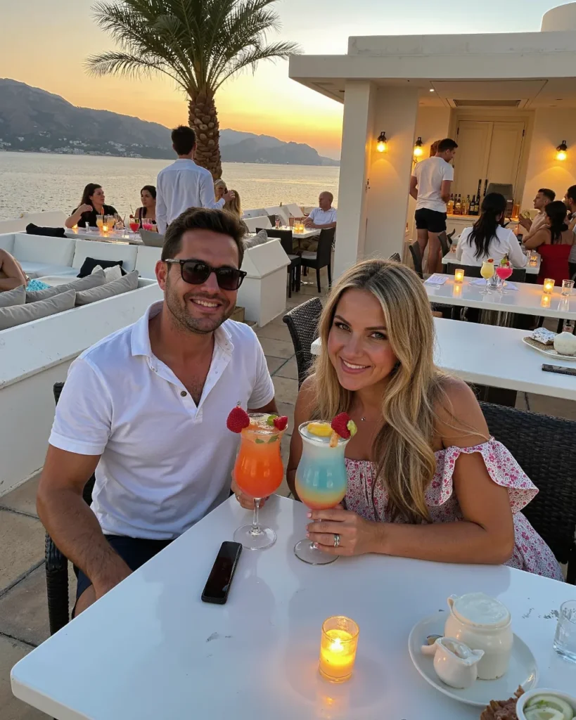 Romantic couple enjoying cocktails at a seaside restaurant in Greece during sunset – the perfect milestone anniversary celebration.
