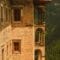 Stone mountain building with a red-tiled roof and arched balcony overlooking a forested valley on a hillside.