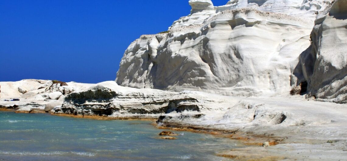 White limestone cliffs along a calm turquoise bay under a clear blue sky (coastal landscape).