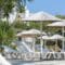 Rows of white lounge chairs under thatched umbrellas at a sunny beach resort. AI
