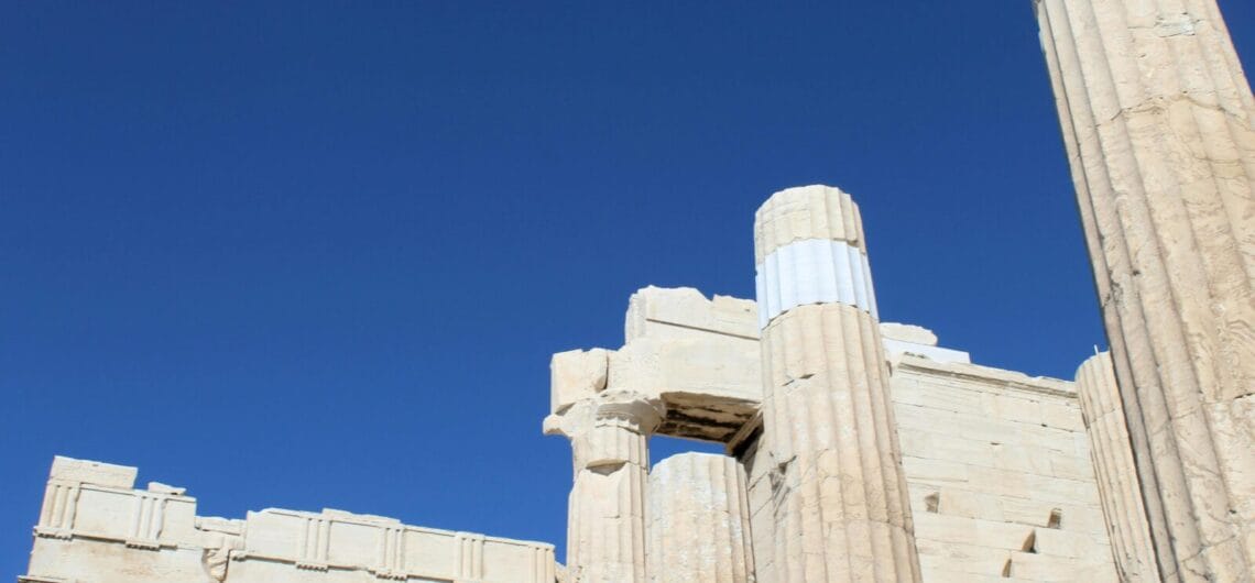 Ruins of an ancient temple with tall fluted marble columns under a clear blue sky